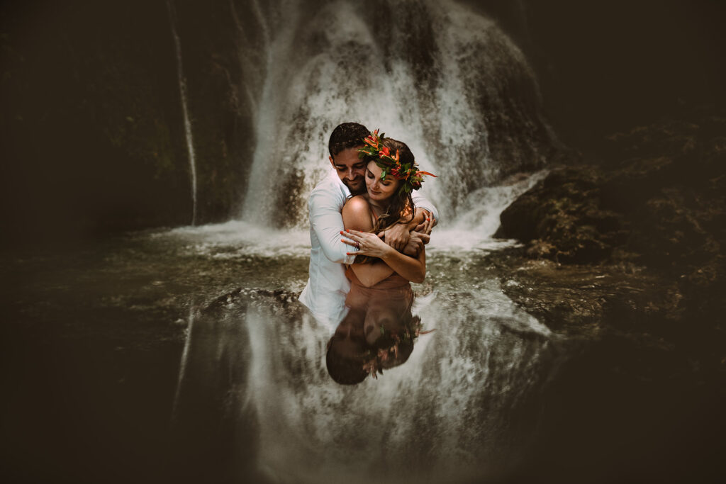 A creative reflexion portrait of a couple standing in front of a waterfall during their pre-wedding photoshoot