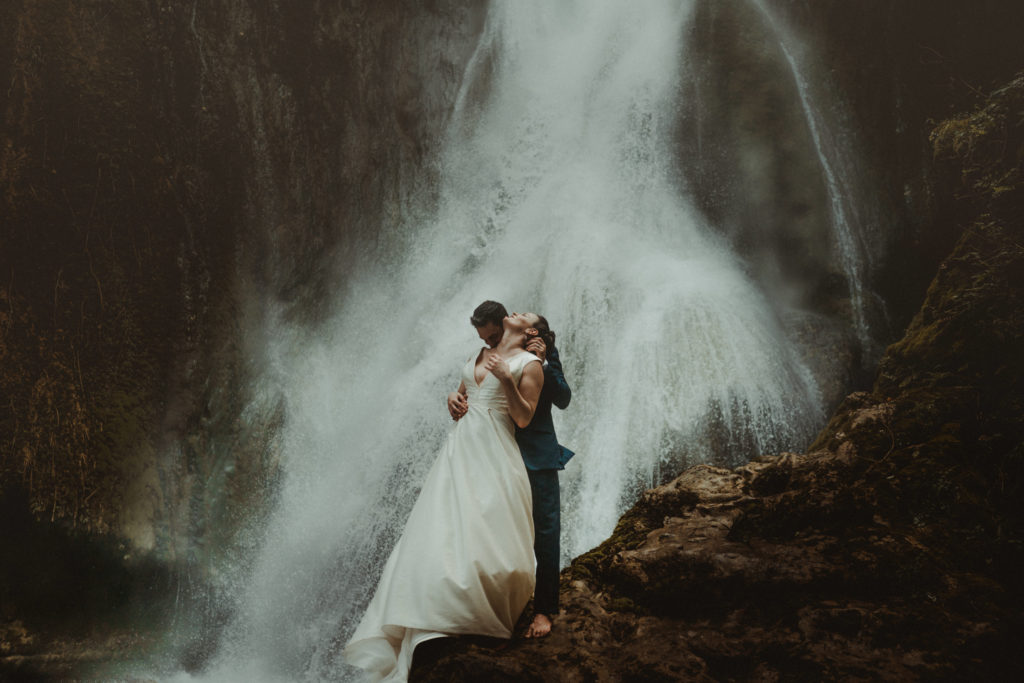 A couple standing in front of a waterfall as they elope in Port Vila.