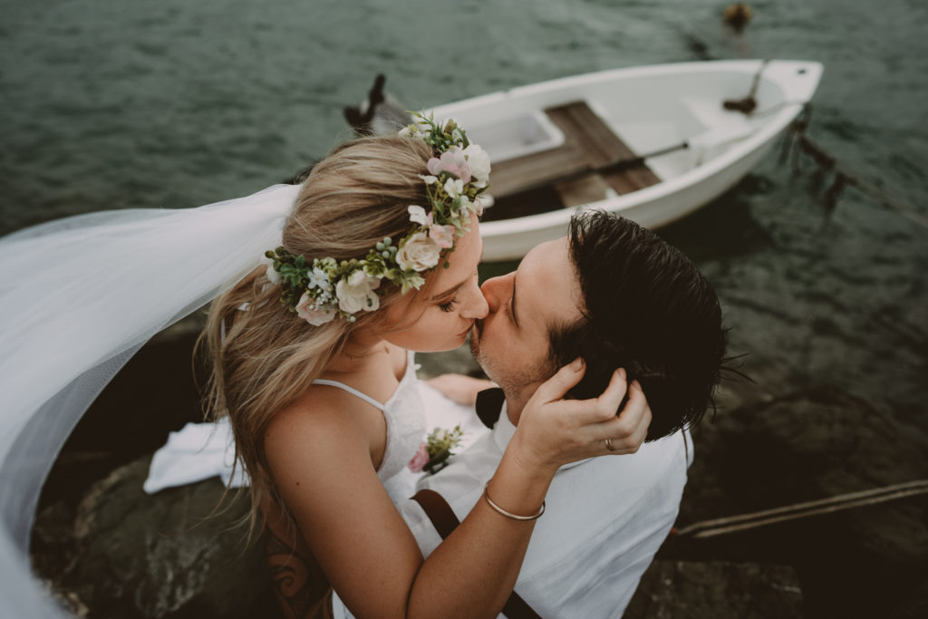 A couple kissing in front of a boat as they elope in Port Vila.