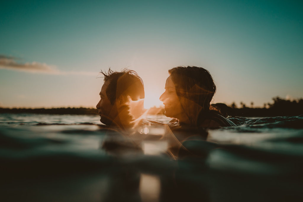 couple taking a swim at sunset on the day of their beach elopement