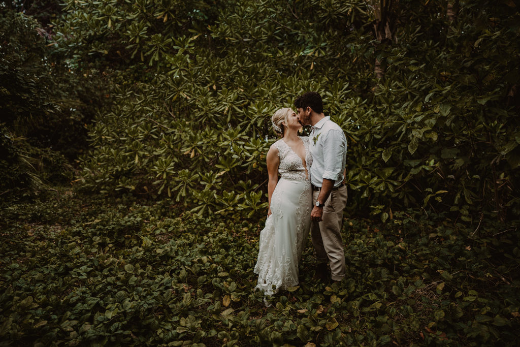 Newlyweds kissing with lush green background on Erakor Island