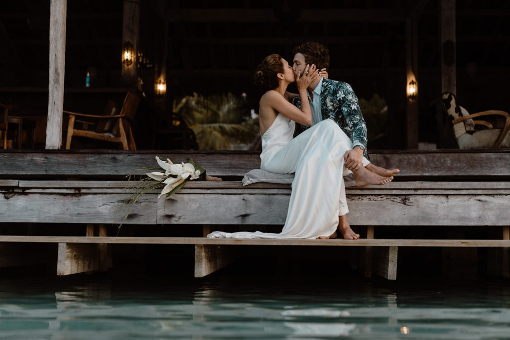 Newlyweds sitting down and kissing on Ratua Island