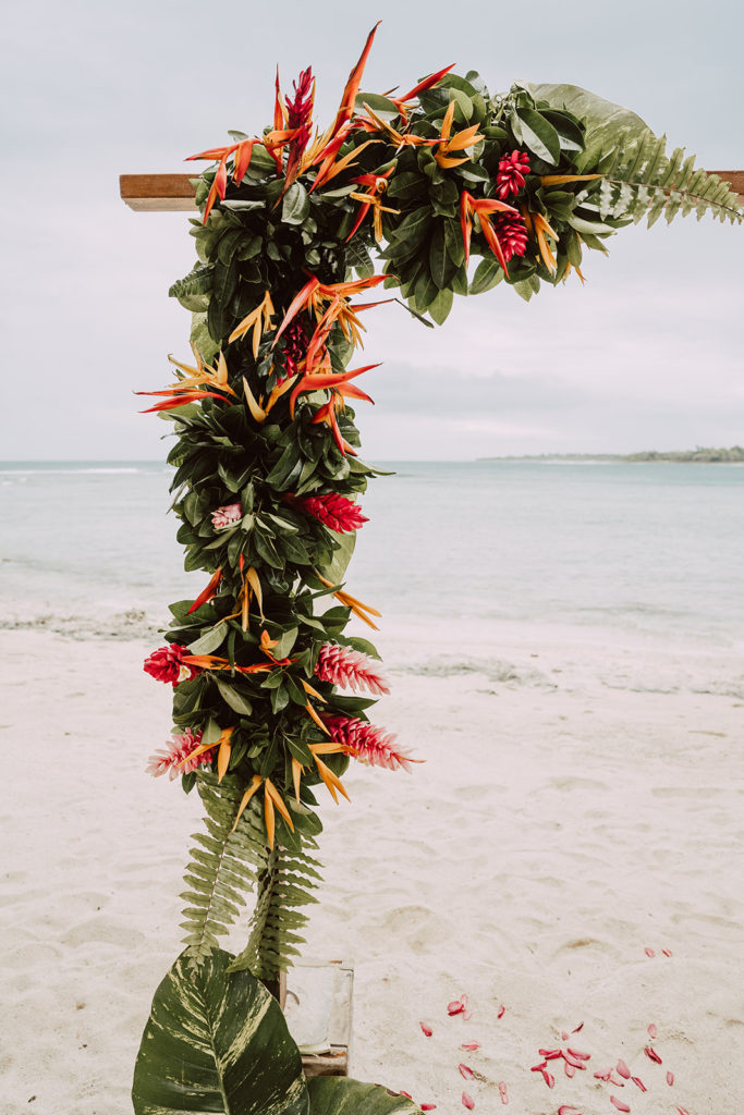 A wedding flower arch with tropical flowers and a beach background 