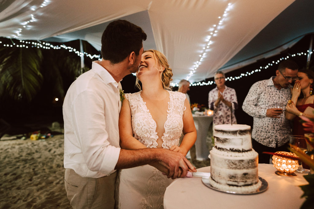 Newlyweds cutting their wedding cake under Erakor island wedding marquee